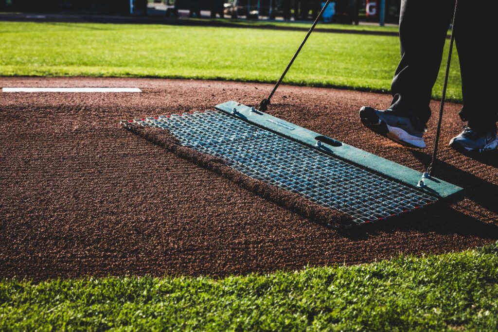 Close up of a pitching mound as a groundskeeper grooms it before practice.